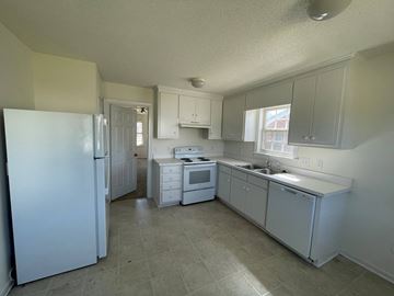 Wilson apartment for rent - A white kitchen with a refrigerator, microwave, sink, and cabinets.