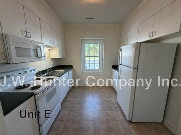 Wilson apartment for rent - A kitchen with white appliances and cabinets is labeled J.W. Hunter Company Inc. Unit E.