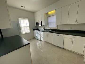 Wilson apartment for rent - A kitchen with white cabinets and black countertops.