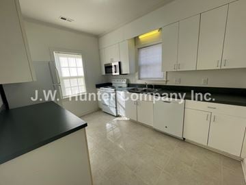 Wilson apartment for rent - A kitchen with white cabinets and a black countertop.