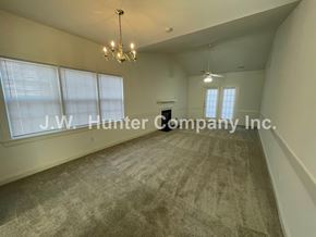 Wilson apartment for rent - A spacious room with a carpeted floor and a chandelier hanging from the ceiling.