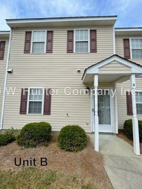 Wilson apartment for rent - A beige house with a white door and windows with shutters.