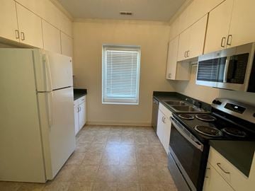 Wilson apartment for rent - A kitchen with white cabinets and black countertops.