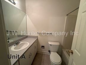 Wilson apartment for rent - A bathroom with a toilet, sink, and mirror.
