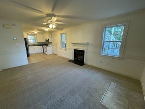 Wilson apartment for rent - A living room with a fireplace and a ceiling fan.