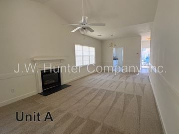 Wilson apartment for rent - A spacious living room with a carpet floor and a ceiling fan.