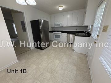 Wilson apartment for rent - A kitchen with white cabinets and a black fridge is shown.