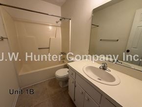 Wilson apartment for rent - A bathroom with a toilet, sink, and mirror.