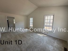 Wilson apartment for rent - A room with carpet flooring and a window with bars on it.