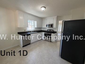 Wilson apartment for rent - A kitchen with white cabinets and a black refrigerator.