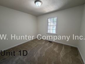 Wilson apartment for rent - A room with a carpeted floor and a window with bars on it.
