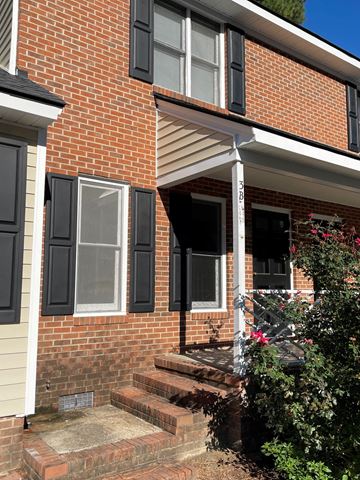 Wilson apartment for rent - A red brick house with a white porch and black shutters.