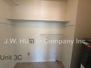 Wilson apartment for rent - A white wall with a shelf and a trash can in front of it.