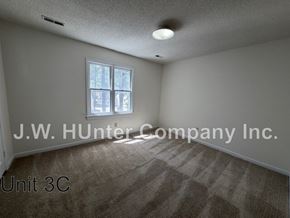 Wilson apartment for rent - A room with a carpeted floor and a window with a view of trees.