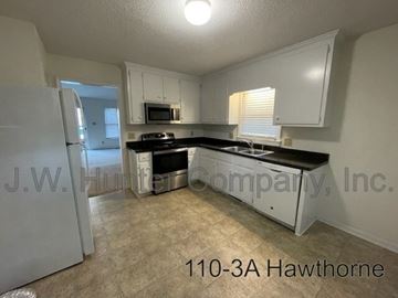 Wilson apartment for rent - A kitchen with white cabinets and black countertops.
