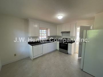 Wilson apartment for rent - A spacious kitchen with white cabinets and a black countertop.
