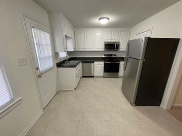 Wilson apartment for rent - A kitchen with white cabinets and a black fridge.