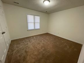 Wilson apartment for rent - A room with a brown carpet and a window.