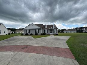 Wilson apartment for rent - A house with a grey roof and white walls is surrounded by a driveway and a grassy area.