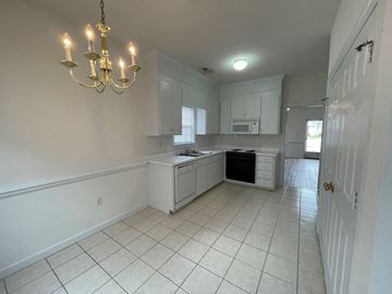 Wilson apartment for rent - A kitchen with white cabinets and a chandelier.
