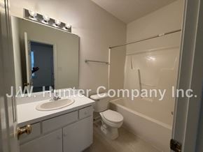Wilson apartment for rent - A white bathroom with a toilet, sink, and mirror.