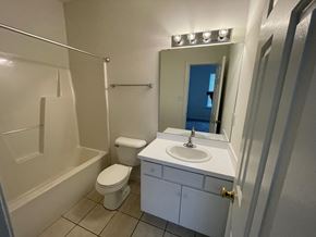 Wilson apartment for rent - A white bathroom with a toilet, sink, and mirror.