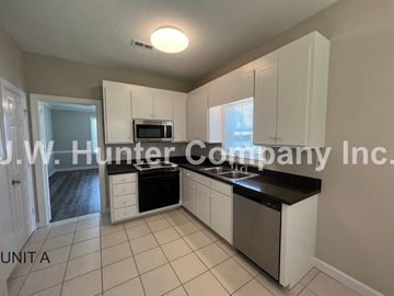 Wilson apartment for rent - A kitchen with white cabinets and black countertops.