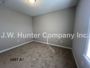 Wilson apartment for rent - A room with carpet flooring and a ceiling light fixture, with the text "J.W. Hunter Company Inc." and "UNIT A" on the wall.