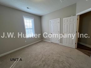 Wilson apartment for rent - A room with carpet flooring and a window with closed white doors.