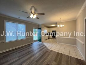 Wilson apartment for rent - A spacious room with a ceiling fan and wooden flooring.