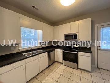 Wilson apartment for rent - A kitchen with white cabinets and black countertops.
