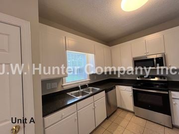 Wilson apartment for rent - A kitchen with white cabinets and black countertops.