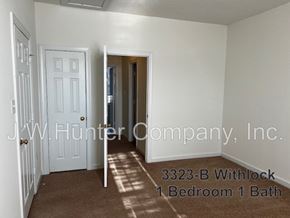 Wilson apartment for rent - A room with a carpet floor and a door leading to another room.