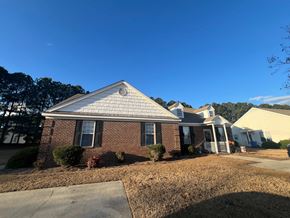 Wilson apartment for rent - A house with a brick facade and a white roof is surrounded by a lawn and other houses.