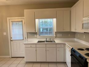 Wilson apartment for rent - A kitchen with white cabinets and a black stove top oven.