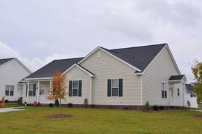 Goldsboro apartment for rent - A house with a grey roof and white walls with a small tree in front.