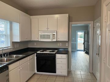 Wilson apartment for rent - A kitchen with white cabinets and black countertops.