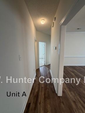 Wilson apartment for rent - A hallway with wood floors and white walls, with text indicating it is Unit A of the Hunter Company.