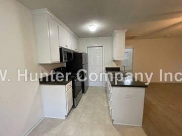 Wilson apartment for rent - A kitchen with white cabinets and appliances, including a black refrigerator and microwave.