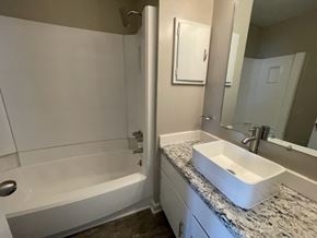 Wilson apartment for rent - A white bathroom with a sink, mirror, and bathtub.