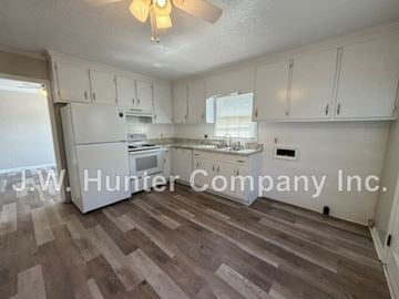 Wilson apartment for rent - A kitchen with white cabinets and a wooden floor.