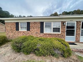 Wilson apartment for rent - A brick house with a green bush in front.