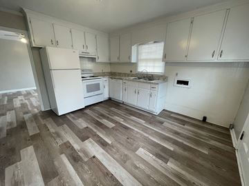 Wilson apartment for rent - A kitchen with white cabinets and a wooden floor.
