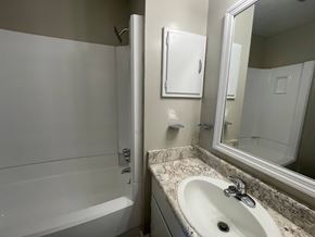 Wilson apartment for rent - A white bathroom with a sink, mirror, and bathtub.