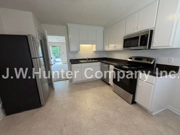 Wilson apartment for rent - A kitchen with white cabinets and black appliances.