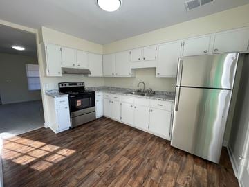 Wilson apartment for rent - A kitchen with white cabinets and a wooden floor.