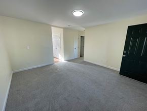 Wilson apartment for rent - A room with a carpeted floor and a black door on the right side.