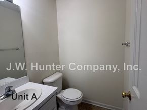 Wilson apartment for rent - A bathroom with a toilet, sink, and a door.