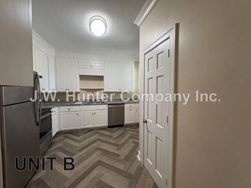 Wilson apartment for rent - A kitchen with white cabinets and a refrigerator in the corner.