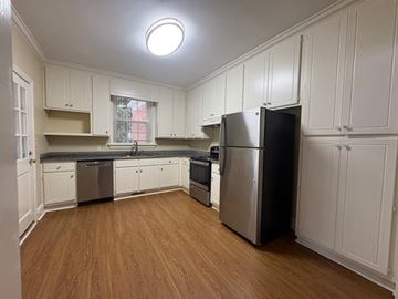 Wilson apartment for rent - A kitchen with wooden floors and white cabinets.